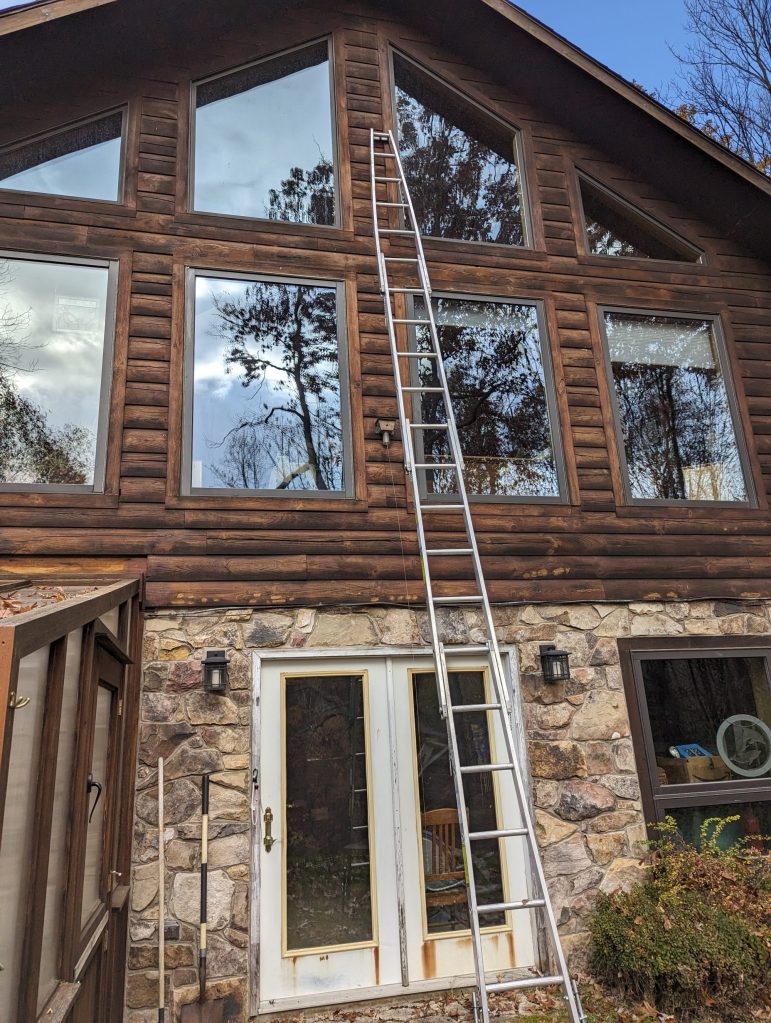 Ladder leaning against log sided home. Many windows on upper levels